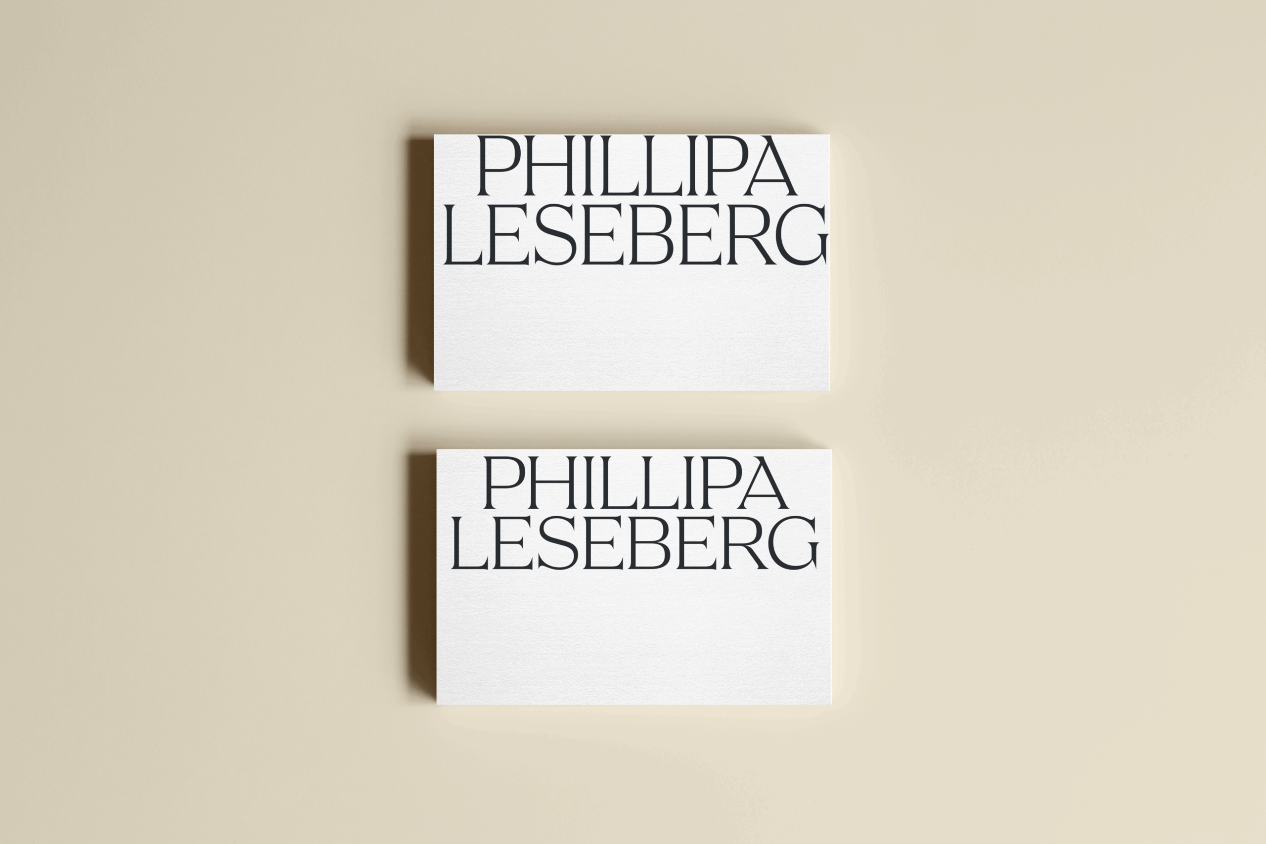 Two white business cards with the name "PHILLIPA LESEBERG" printed in large, bold black letters on a beige background, an example of a vector based logo, designed by Sweet Pea Ink Creative for standout branding.