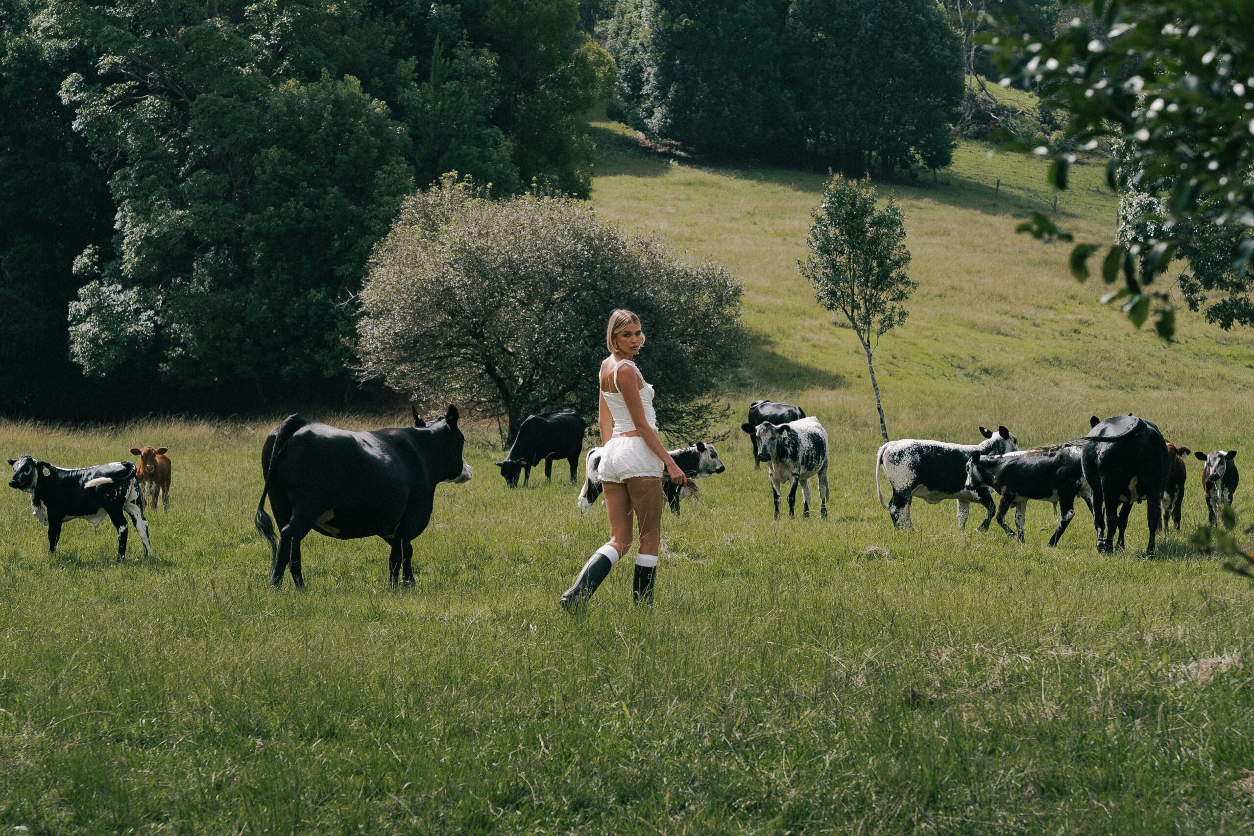 Woman running through pasture surrounded by grazing goats